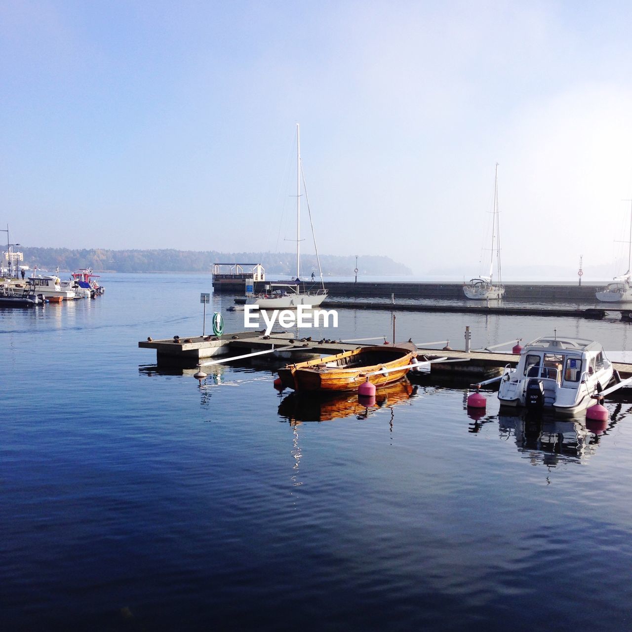 Boats moored by pier in river against sky