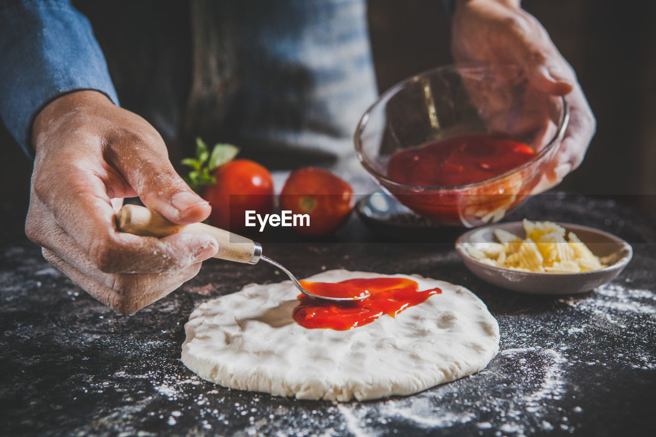 Midsection of man preparing pizza in home