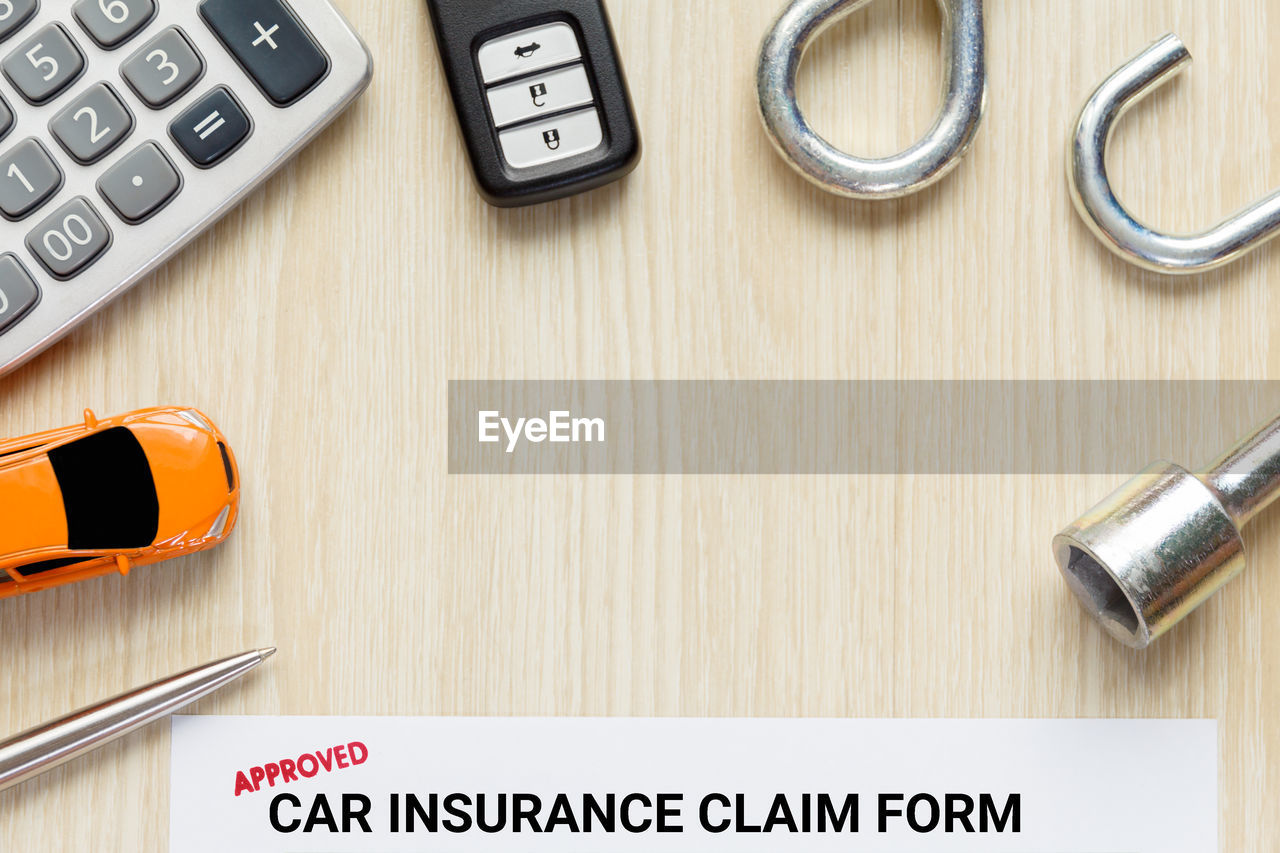 Directly above shot of car insurance claim form with toy and key on table