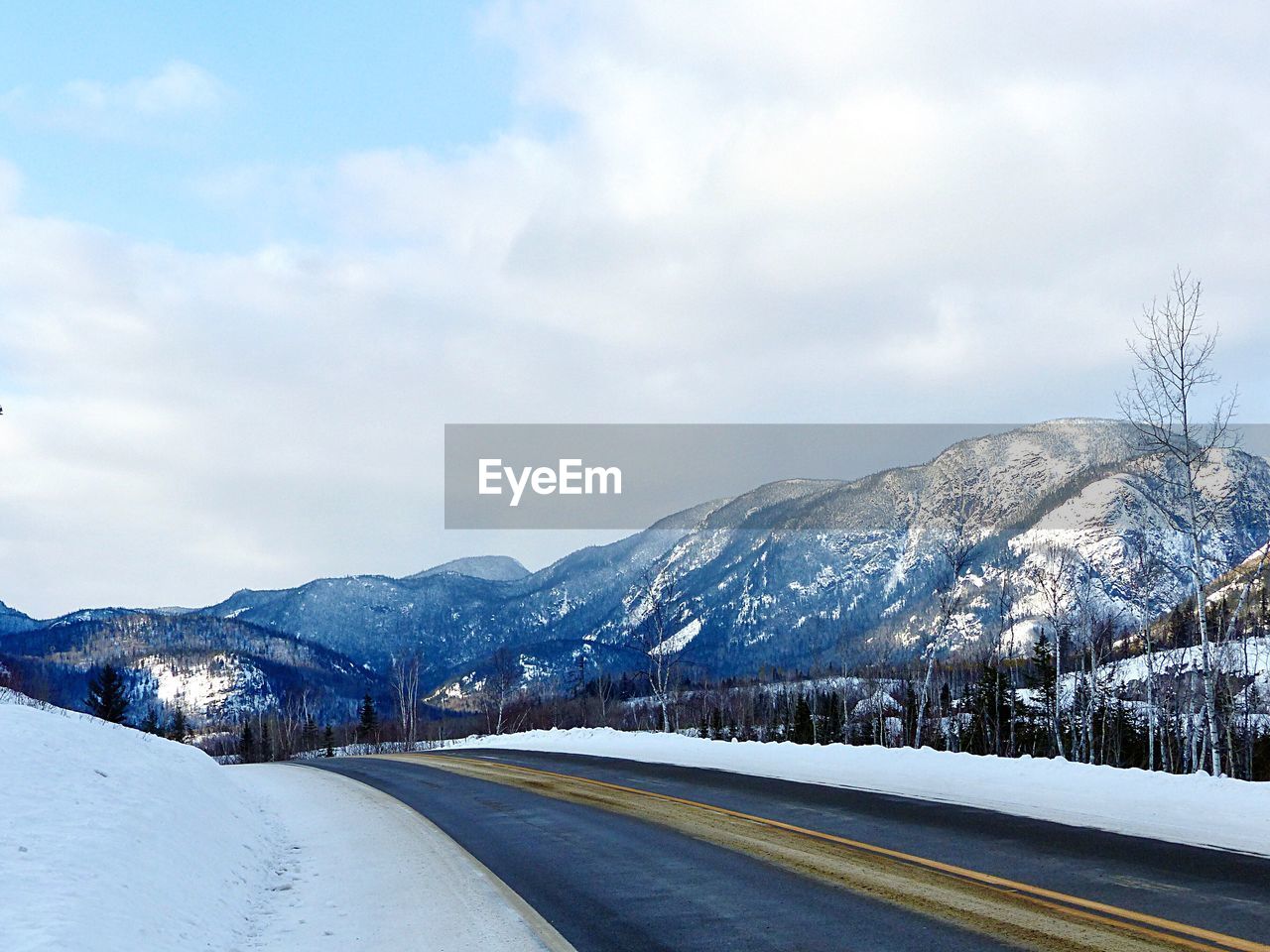 Road leading towards snowcapped mountains against sky