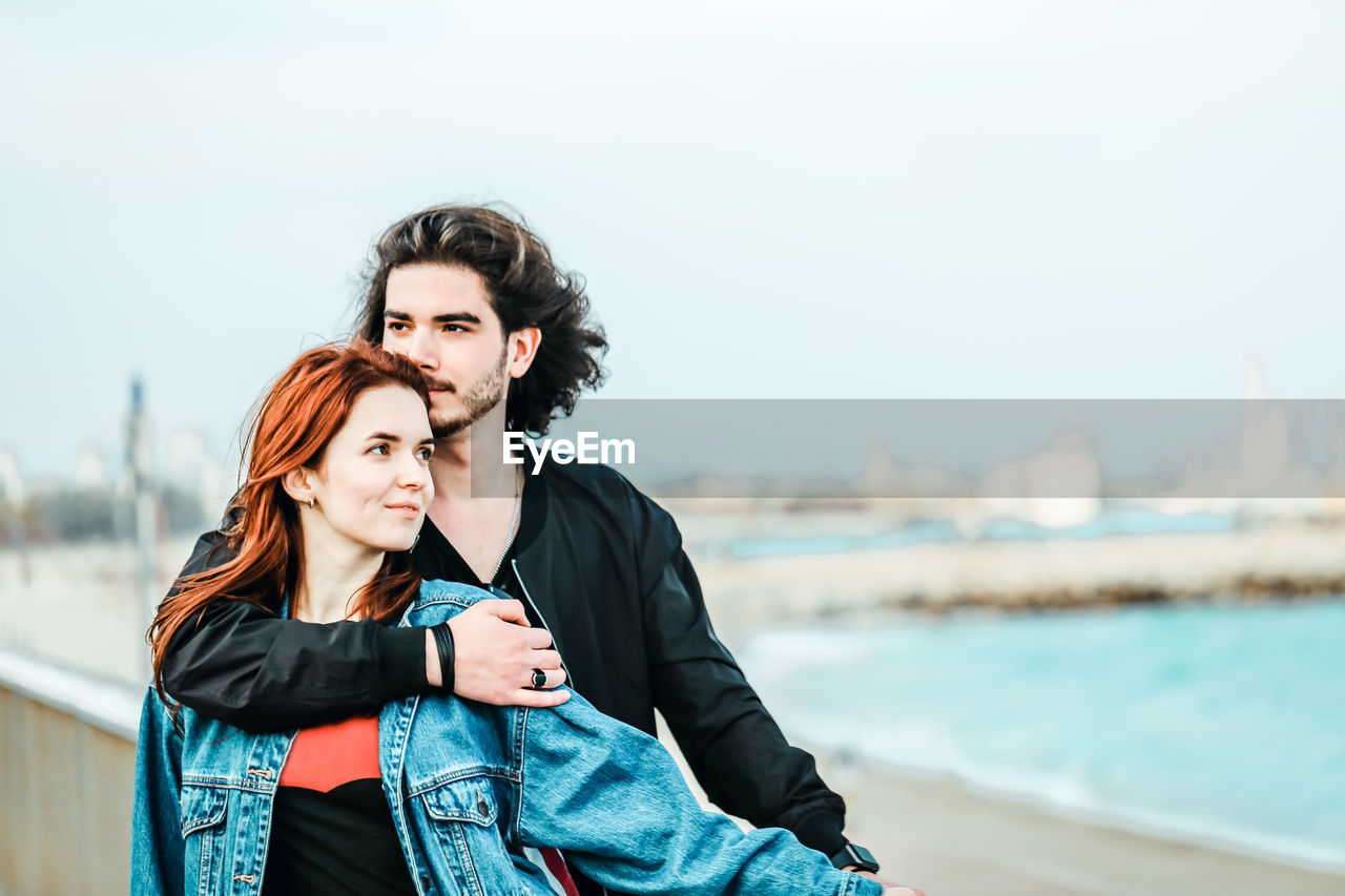 Young couple standing against sky