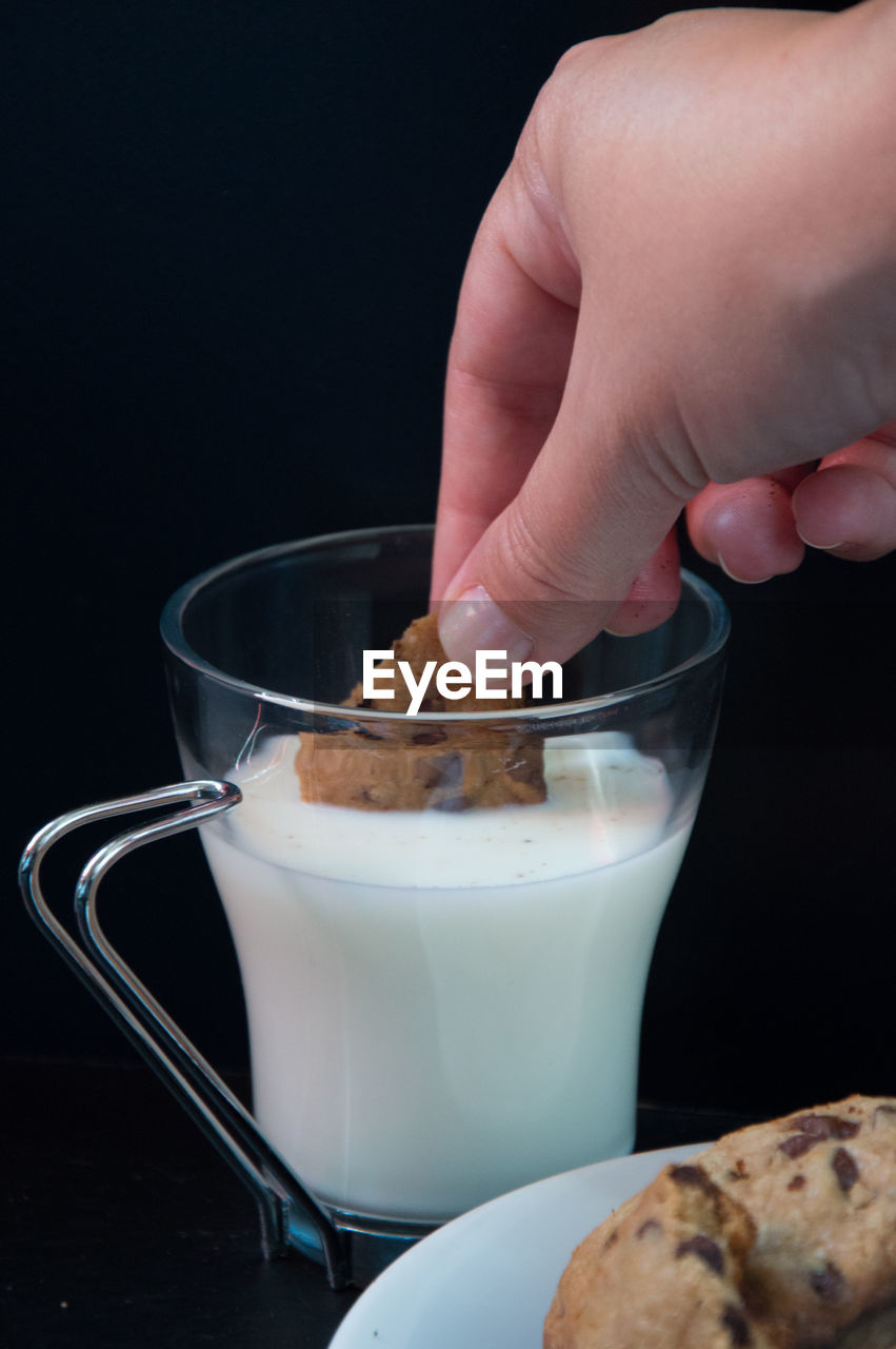 Cropped hand having cookies with milk