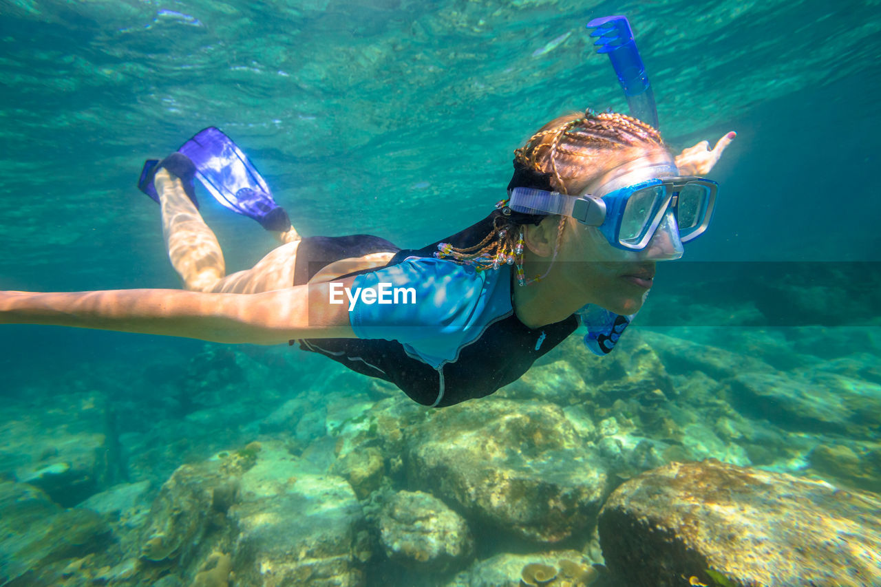 Woman snorkeling over rocks undersea