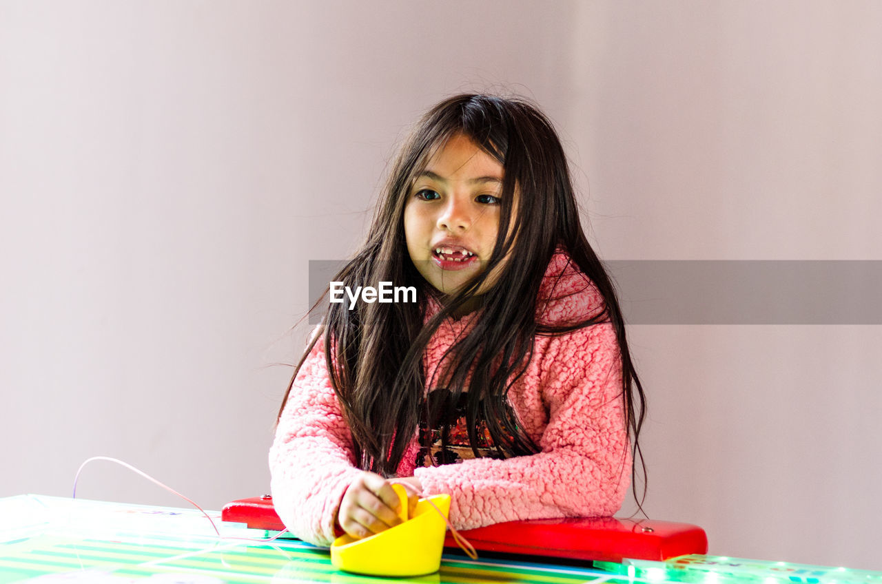 Cute girl looking away while sitting indoors