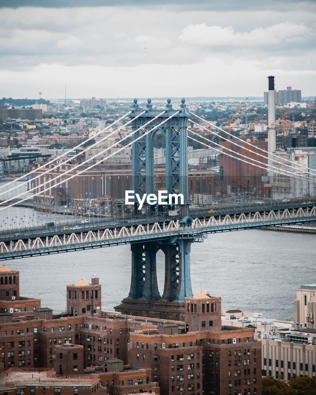 Bridge over river in city against cloudy sky