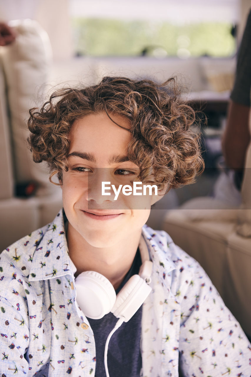 Close-up of thoughtful smiling man with headphones looking away in van