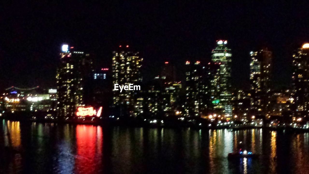 ILLUMINATED CITY BY RIVER AGAINST SKY