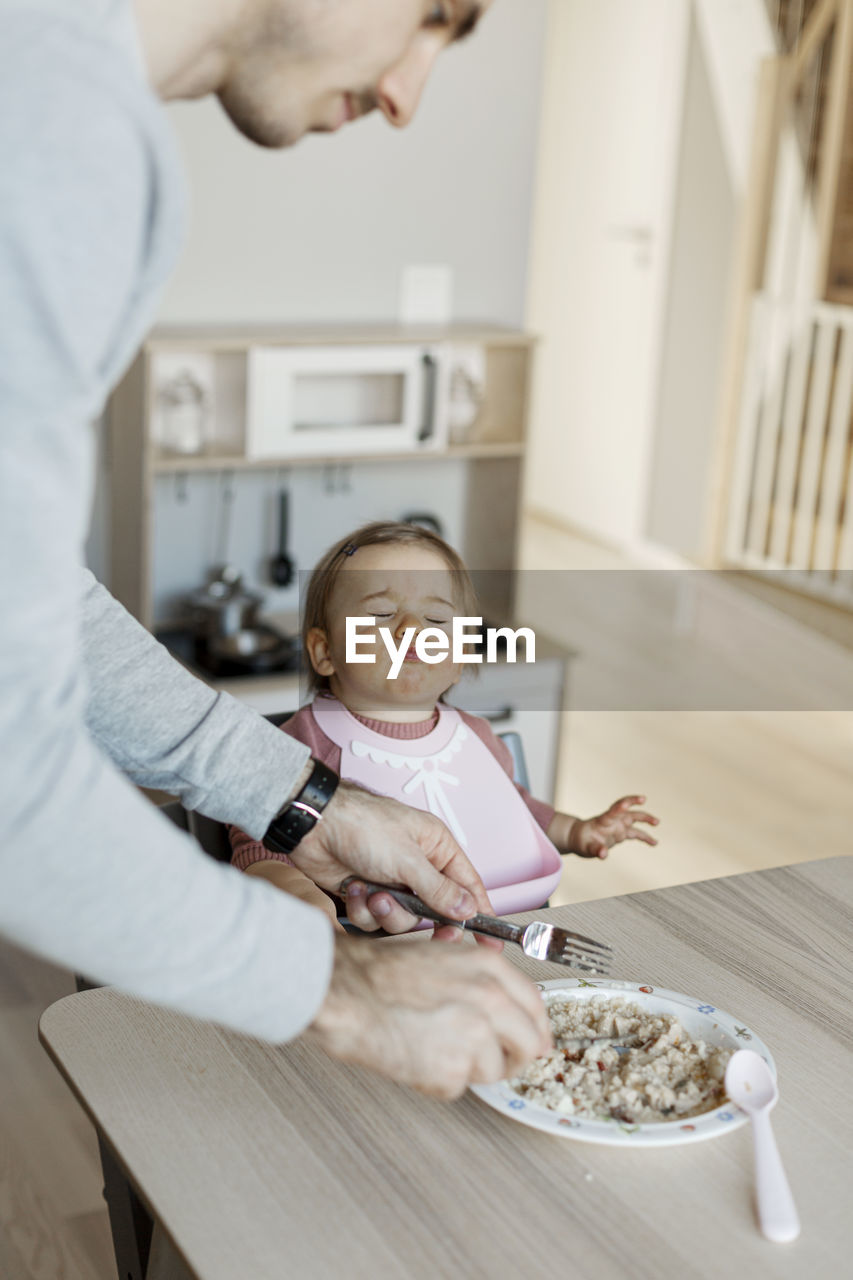 Father feeding toddler daughter