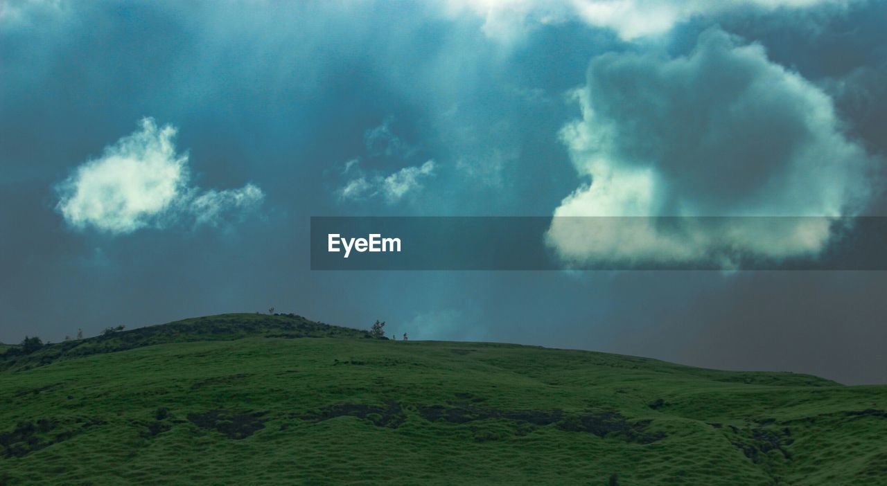 GREEN LANDSCAPE AGAINST CLOUDY SKY