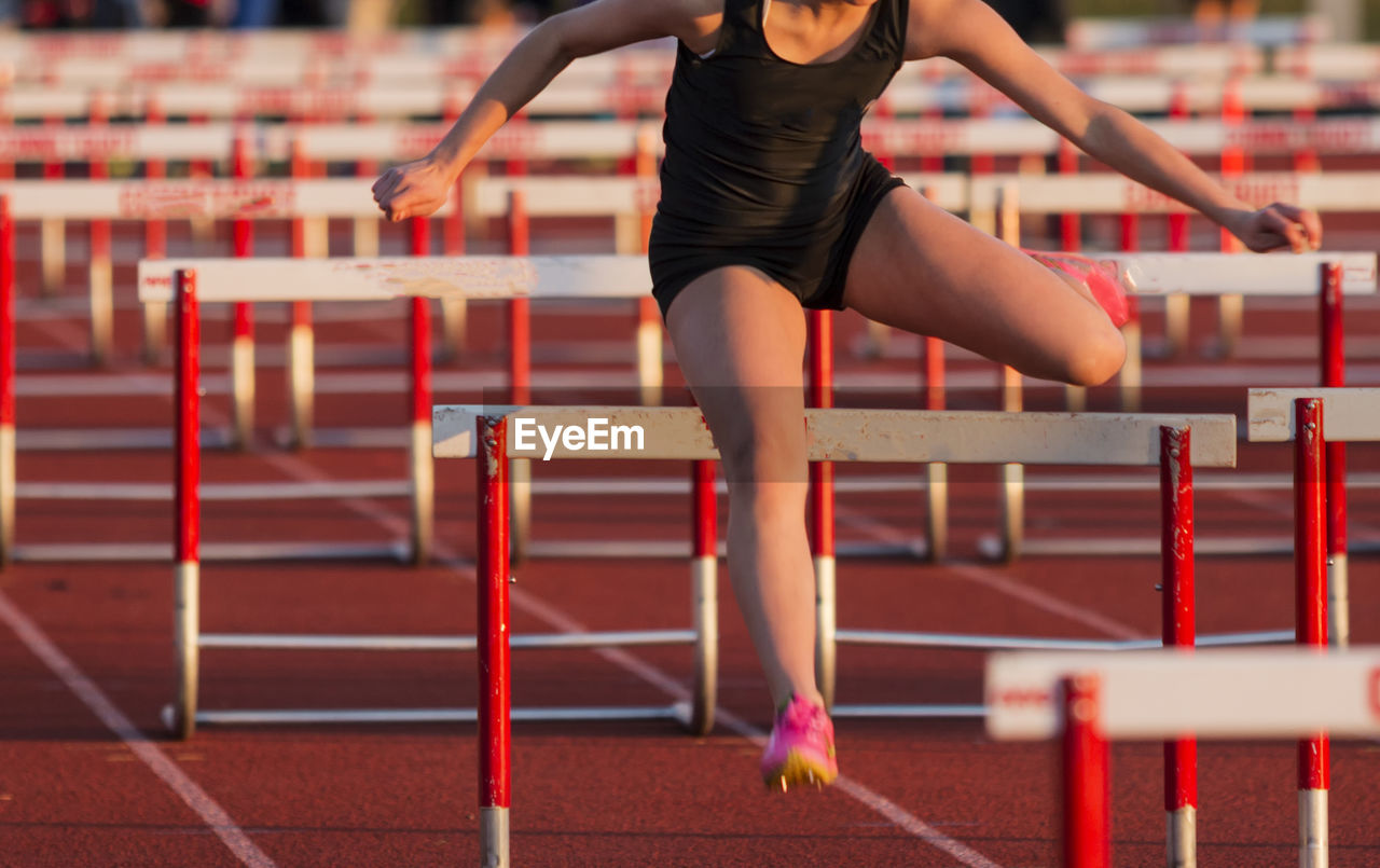 A high school girls racing the 100 meter hurdles during a pentathlon competition at a track meet.