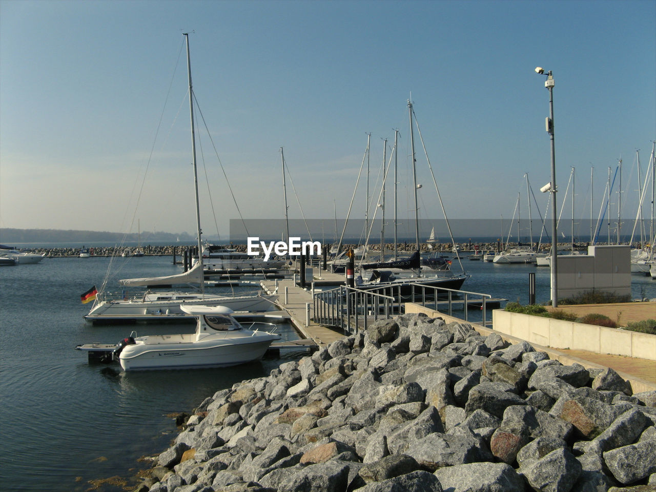 Sailboats moored at harbor in sea against sky