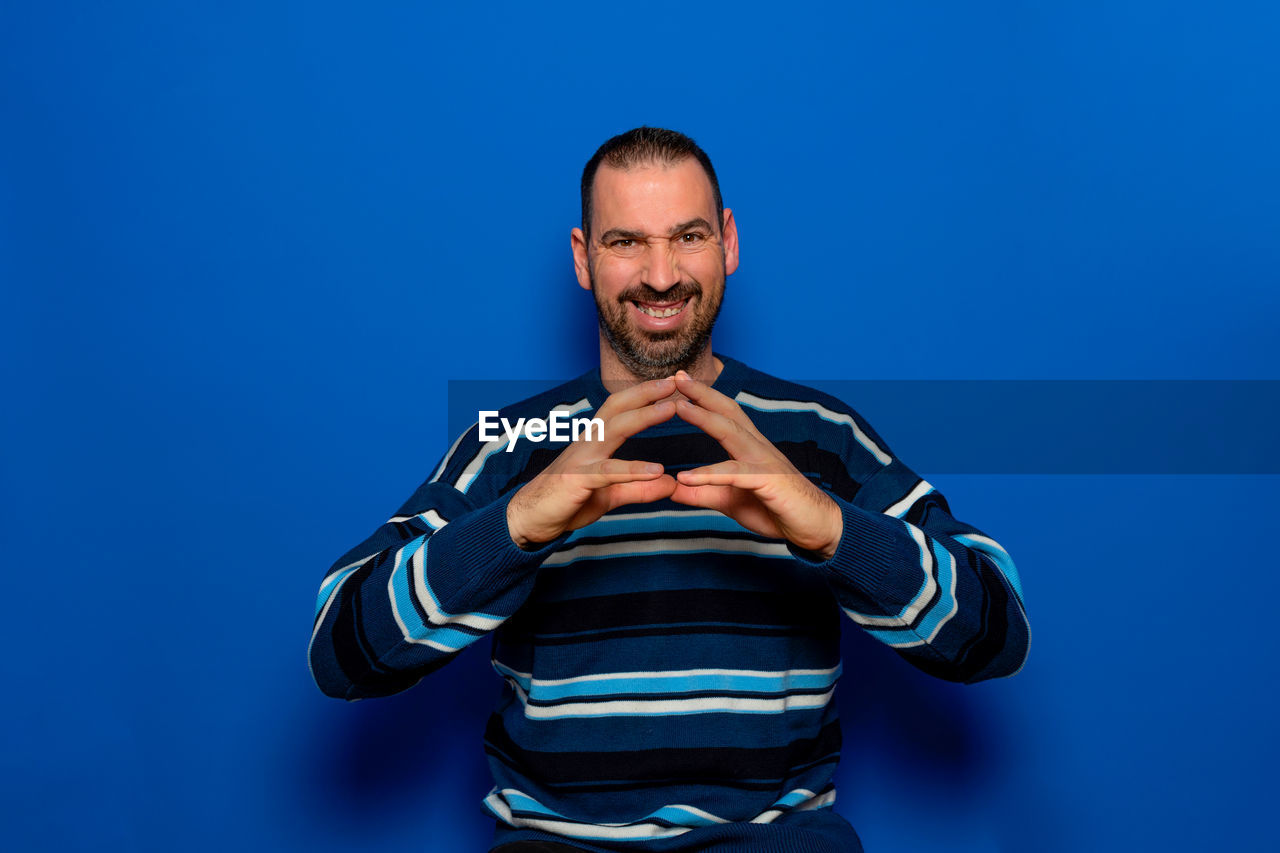 blue, one person, adult, studio shot, portrait, men, colored background, blue background, looking at camera, front view, indoors, sports, waist up, emotion, young adult, smiling, athlete, happiness, clothing, copy space, facial hair, beard, lifestyles, person, standing, strength, hand, vitality, muscular build, sports clothing