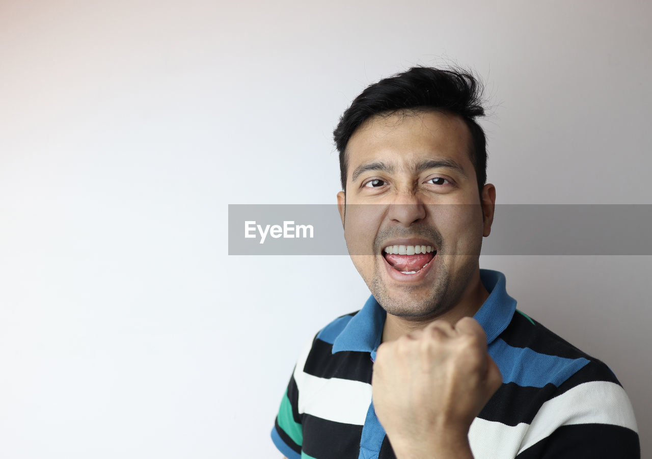 PORTRAIT OF HAPPY MAN AGAINST WHITE BACKGROUND