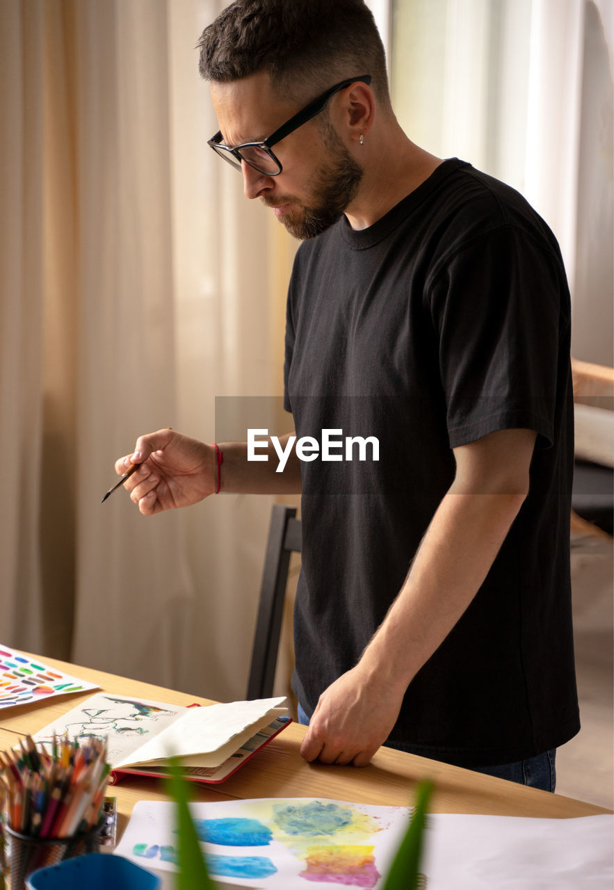 Midsection of man holding eyeglasses while standing on table