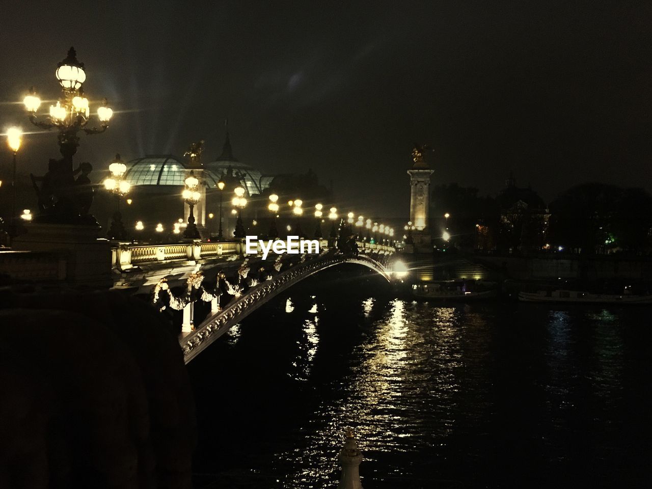 ILLUMINATED BRIDGE OVER CITY AGAINST SKY AT NIGHT