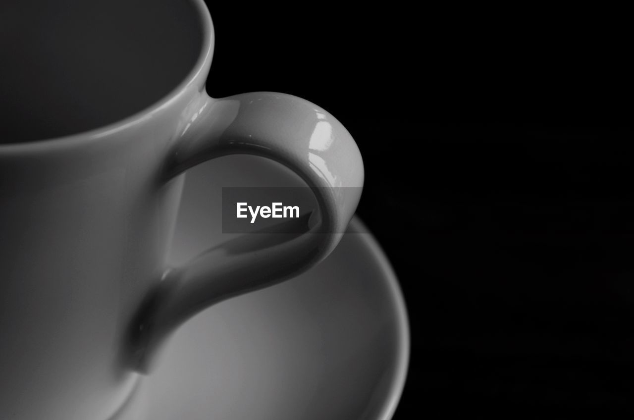 Close-up of coffee cup on saucer against black background