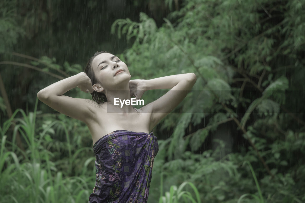 Woman with hand in hair standing outdoors during rainy season