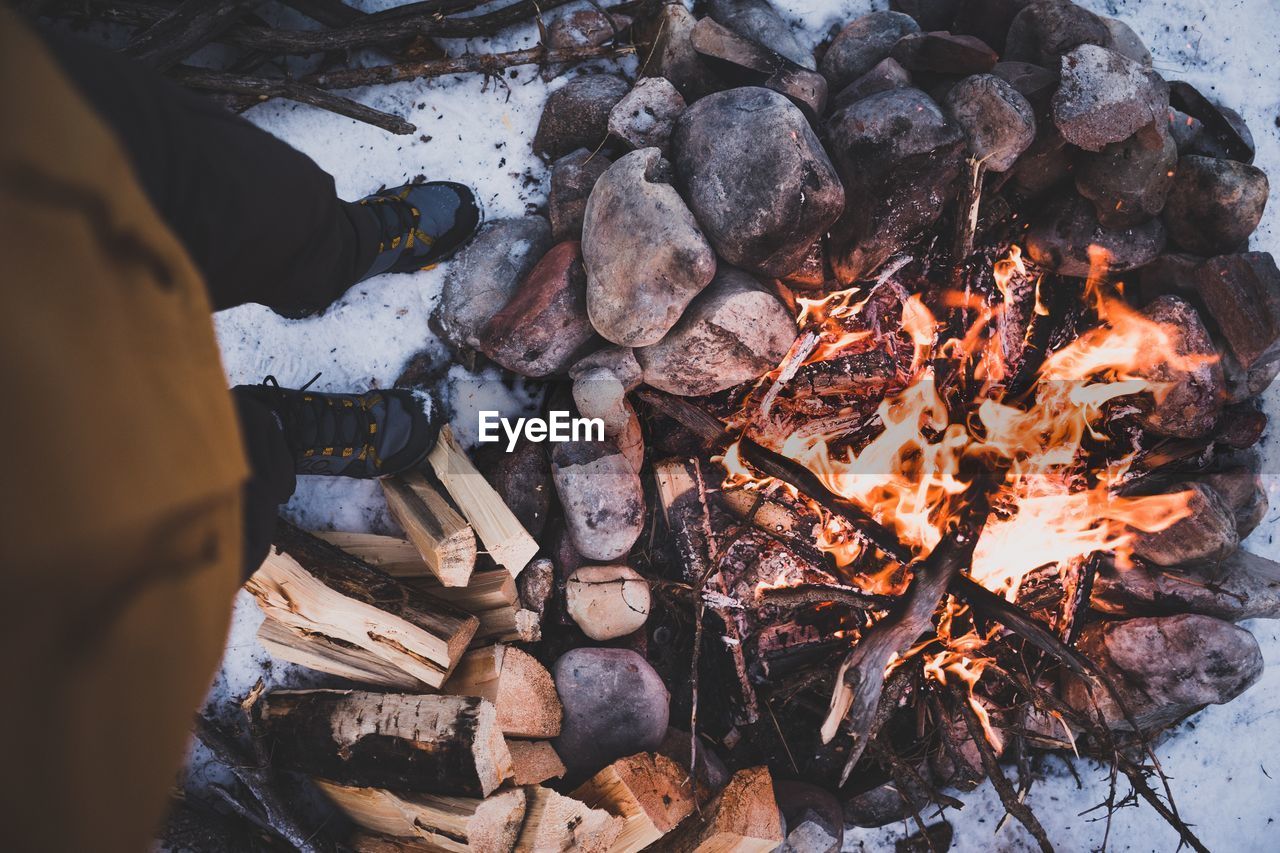 Low section of man standing by bonfire during winter