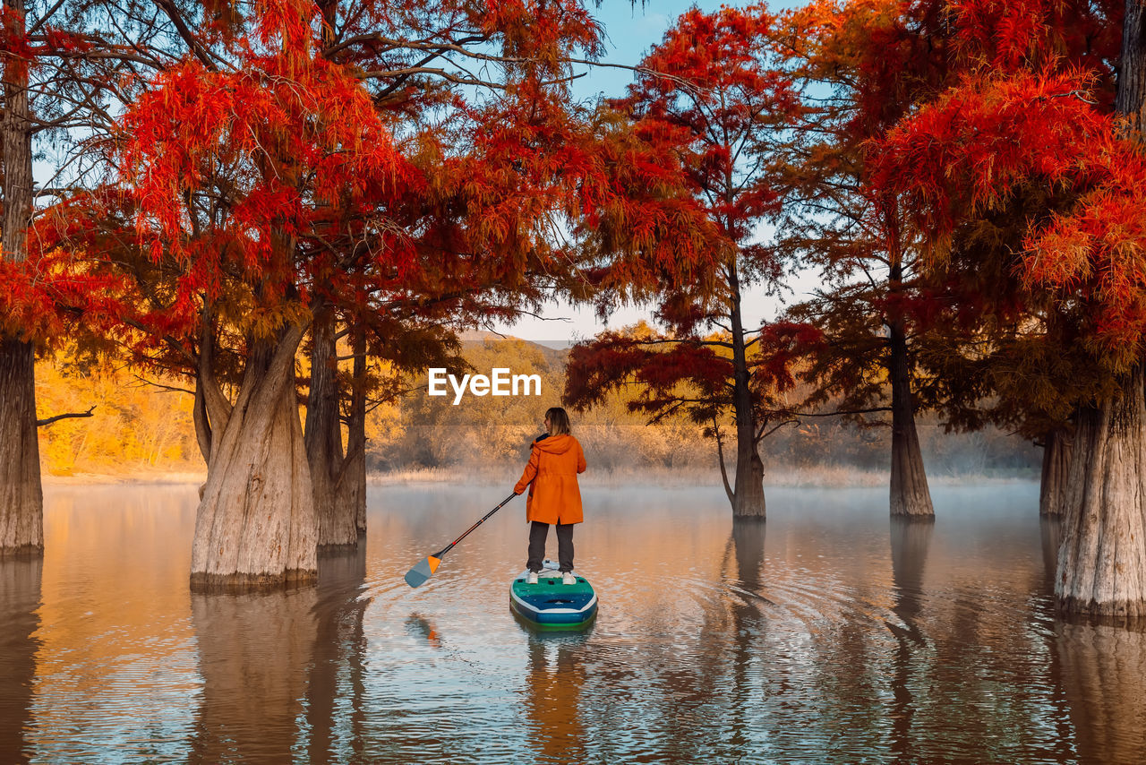 rear view of woman standing by lake during autumn