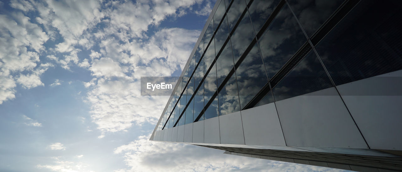 LOW ANGLE VIEW OF GLASS BUILDING AGAINST CLOUDY SKY