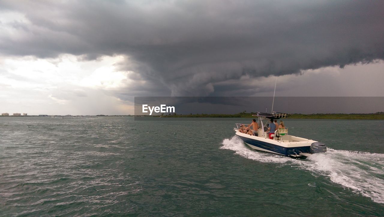 Motorboat in sea against cloudy sky