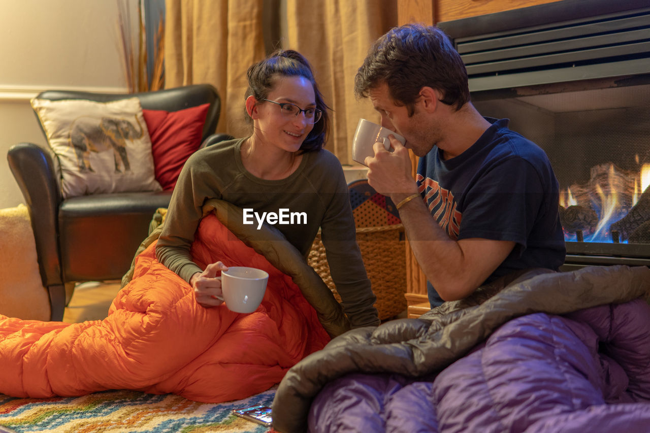 YOUNG COUPLE SITTING ON BED IN BEDROOM