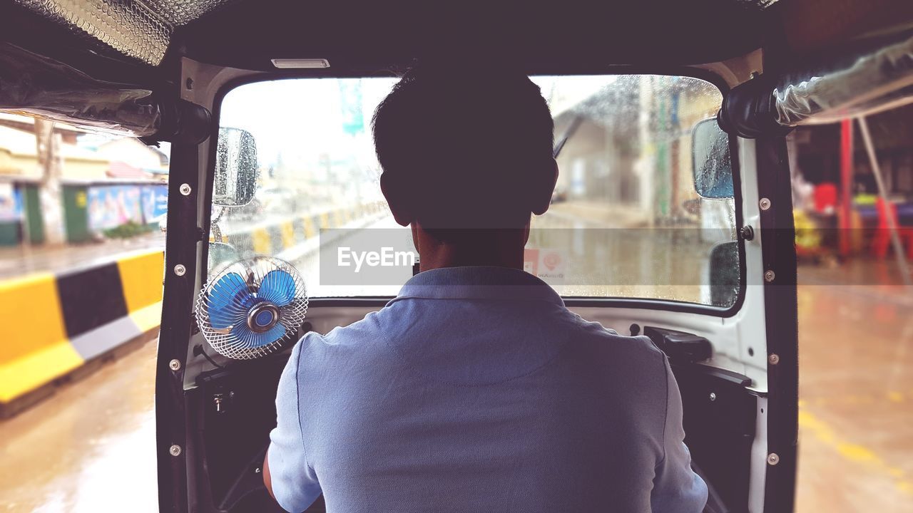 Rear view of man driving jinrikisha on street