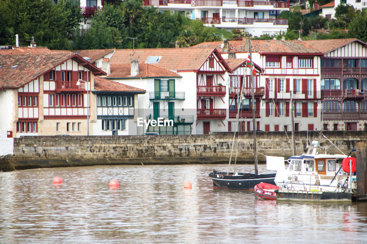 BOATS MOORED ON RIVER BY BUILDINGS