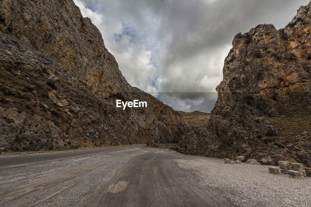 ROAD AMIDST ROCKS AGAINST SKY