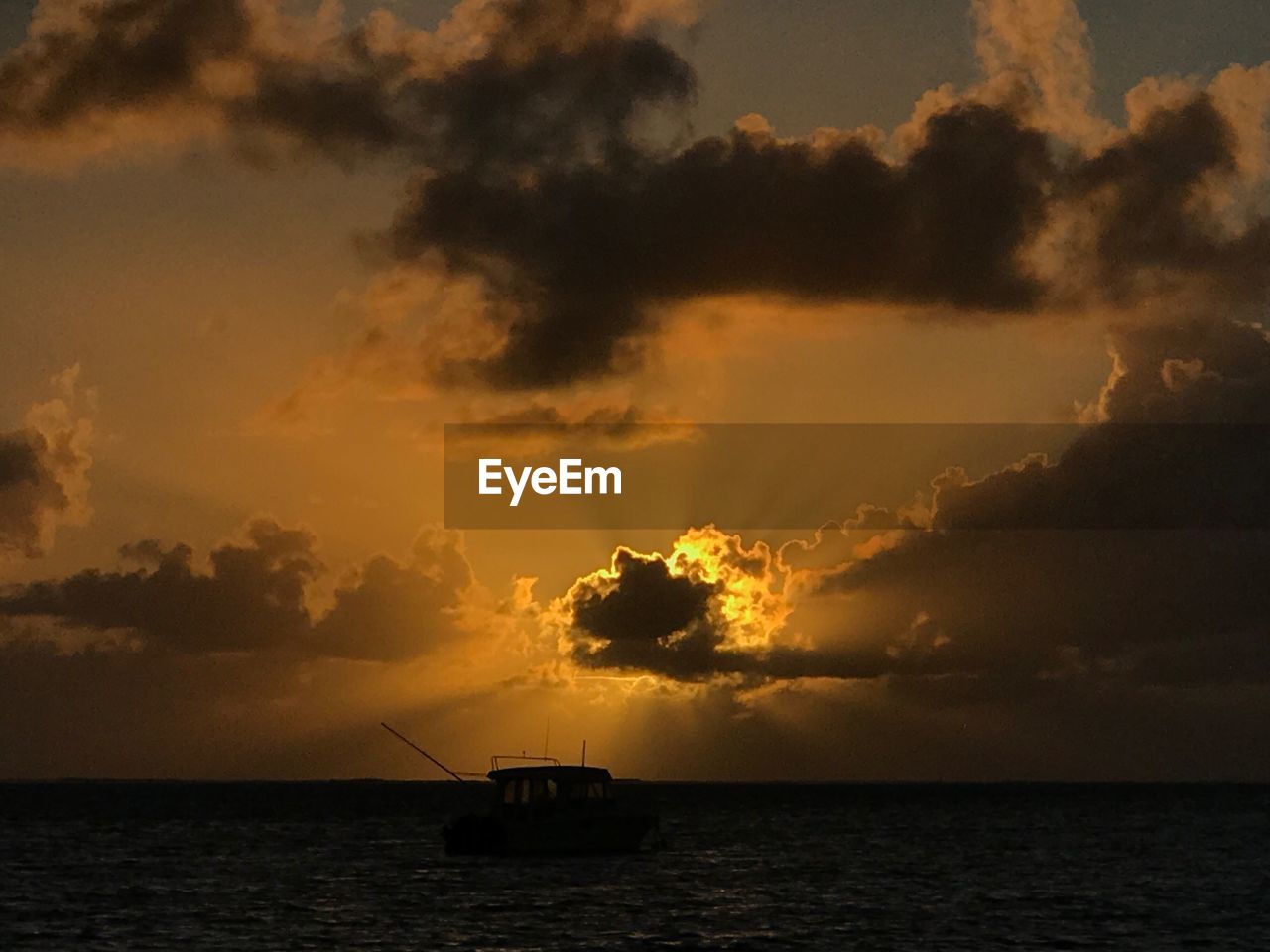 Silhouette boat in sea against sky during sunset