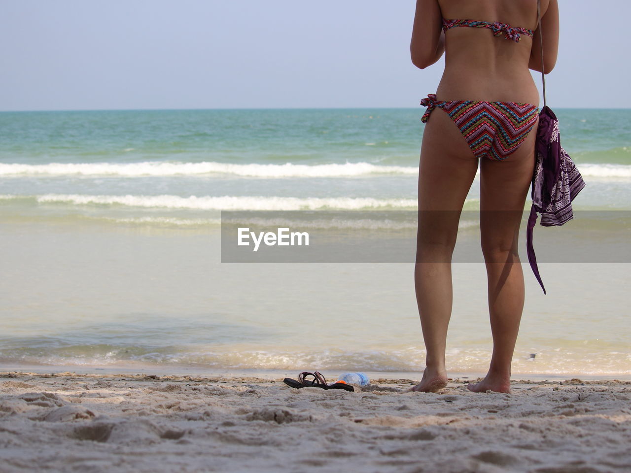 Low section of woman standing on beach against sky