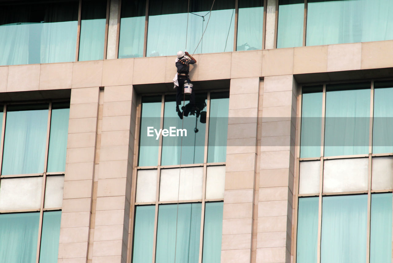 A worker cleaning window glass of a high rise building corporate office