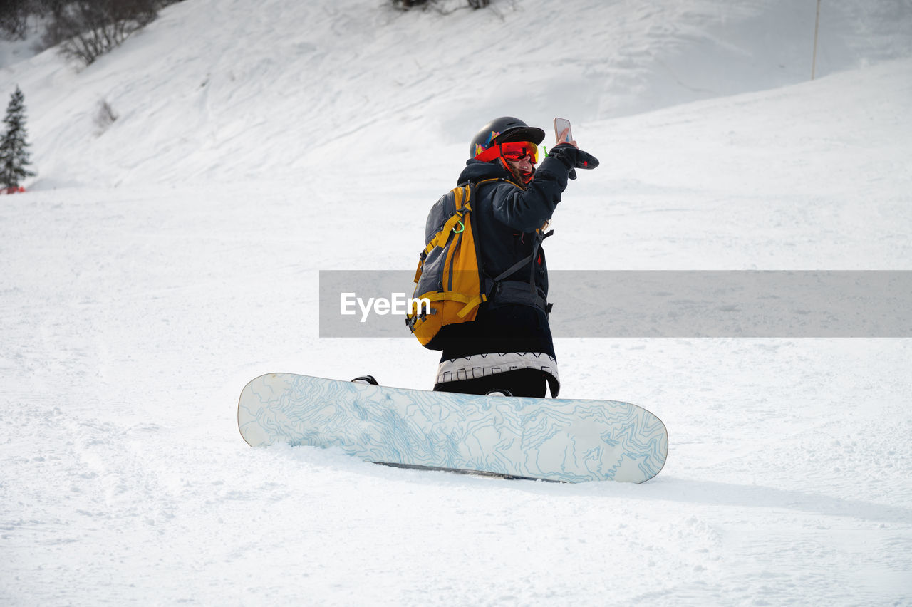 Snowboarder sits on a mountain and takes pictures. winter landscape in the french alps. beautiful