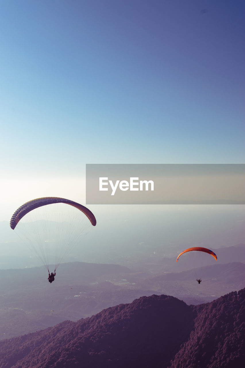 People paragliding over mountain against sky