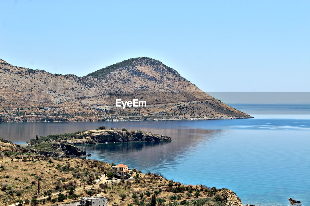 Scenic view of sea and mountains against clear blue sky