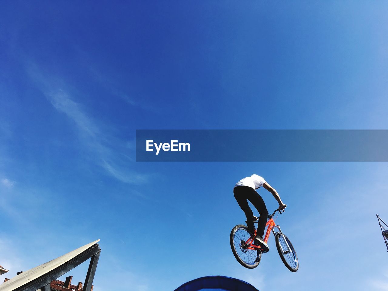 LOW ANGLE VIEW OF MAN PARAGLIDING AGAINST BLUE SKY