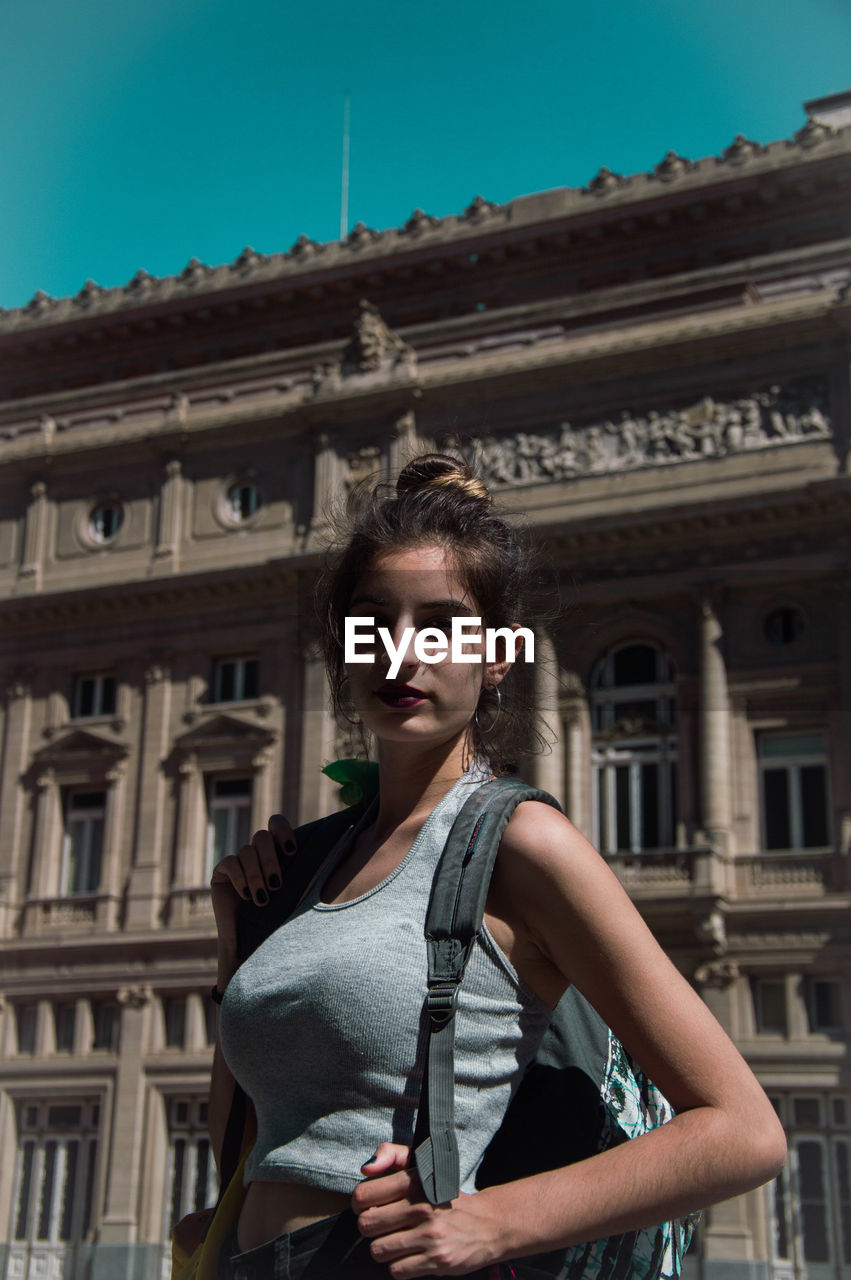 PORTRAIT OF BEAUTIFUL WOMAN STANDING AGAINST BUILDING