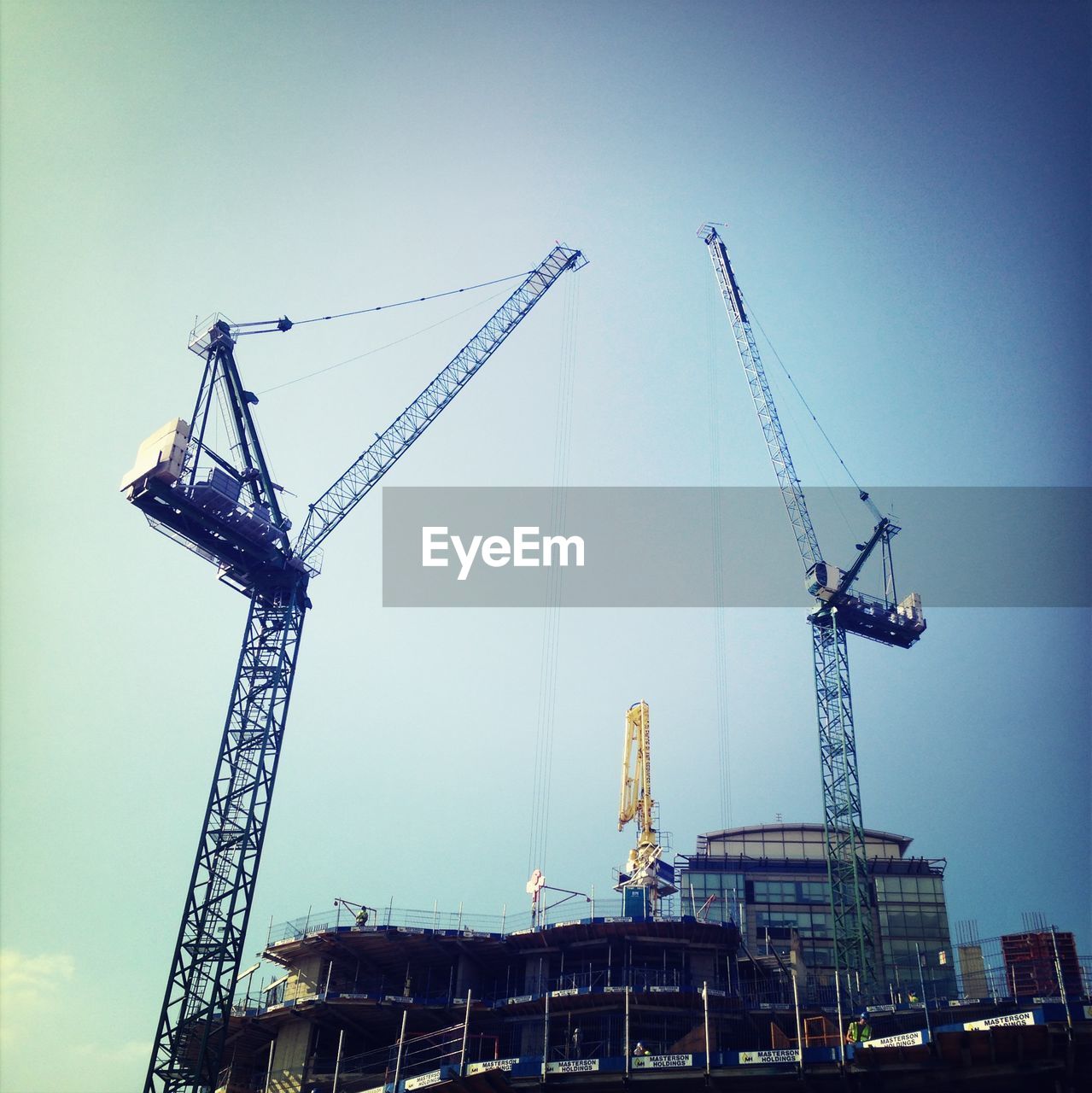 Low angle view of crane at construction site against clear sky