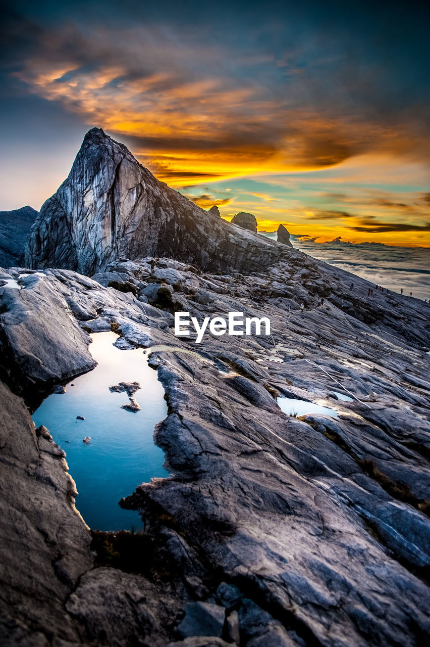 SCENIC VIEW OF SEA BY SNOWCAPPED MOUNTAIN AGAINST SKY DURING SUNSET