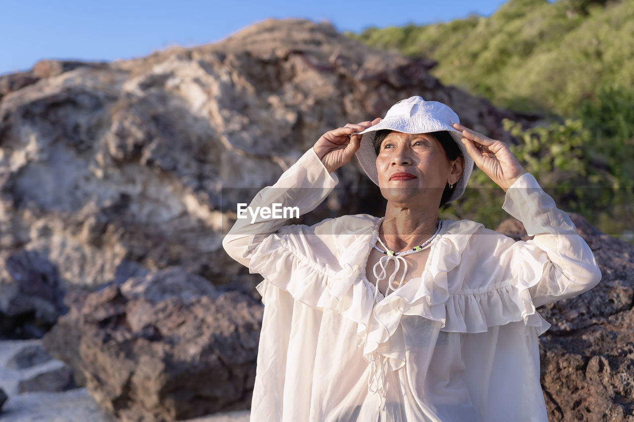 Portrait of a happy mature woman smiling outdoors. happy smiling mature woman on the rock 