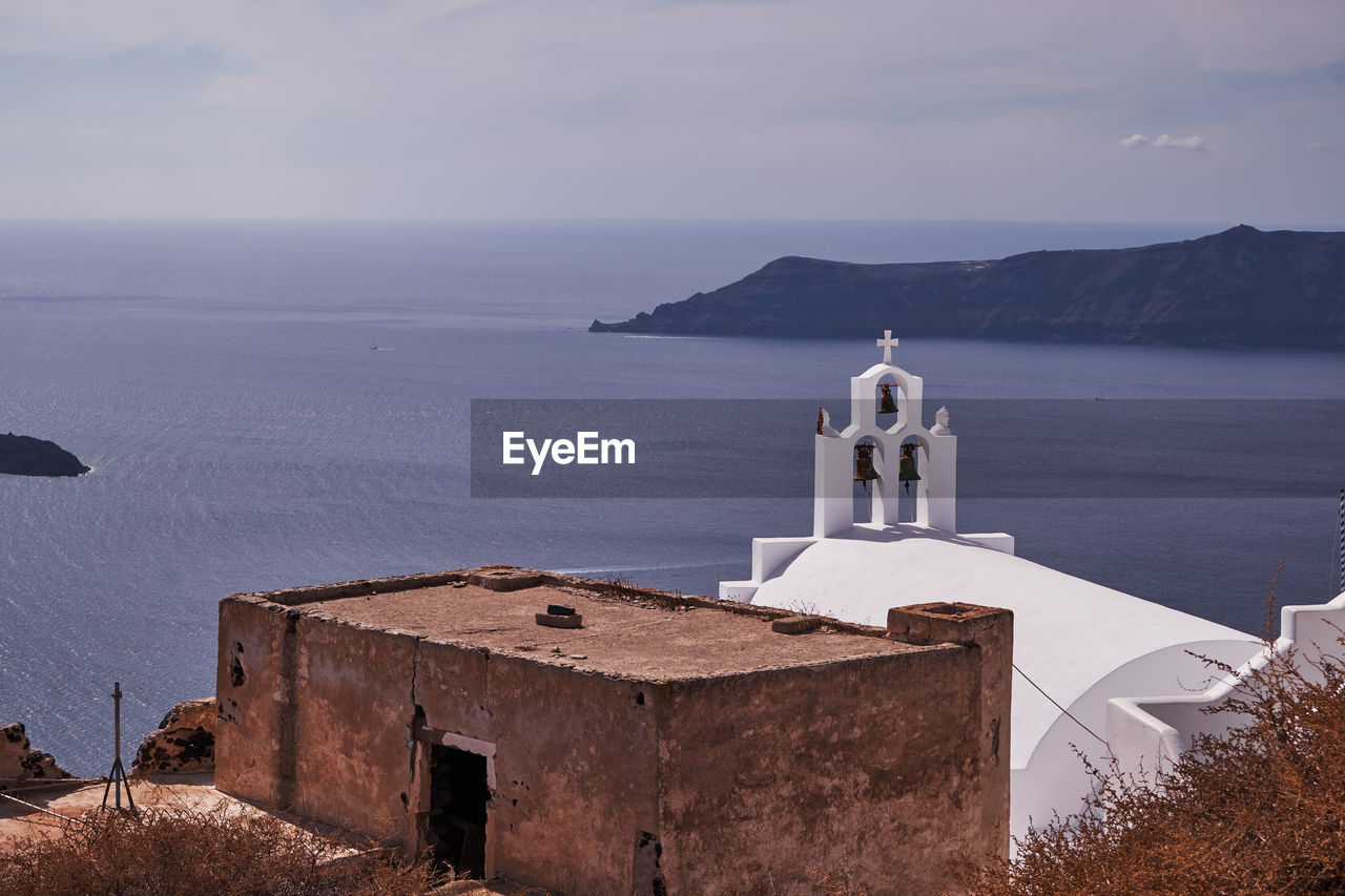 Small church with its three bells tower in imerovigli village - santorini island, greece