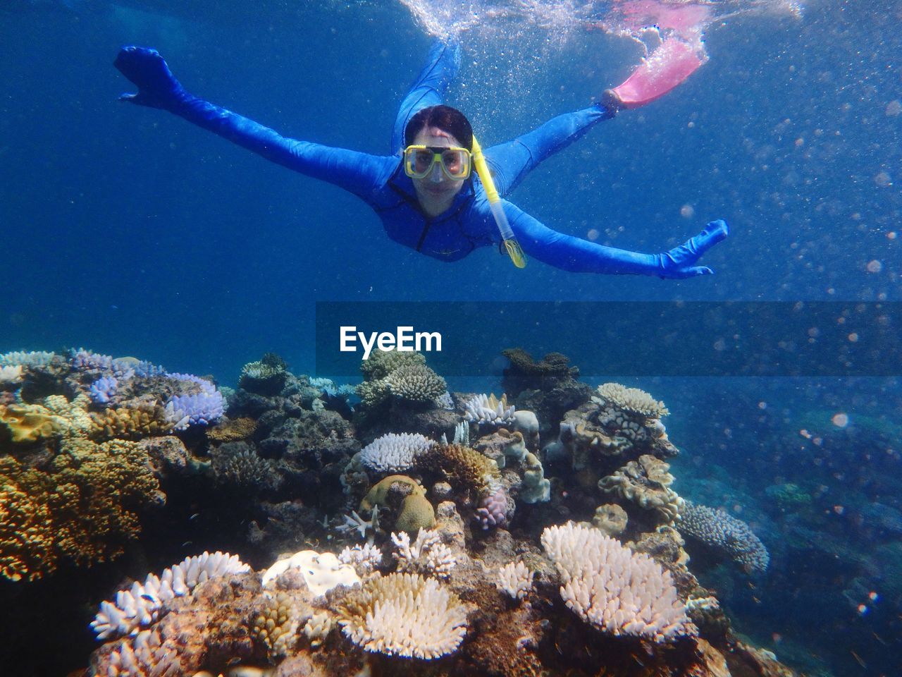 Full length portrait of woman with arms outstretched snorkeling in sea