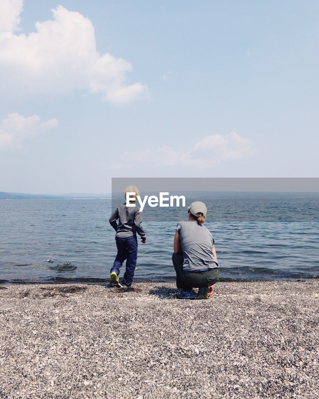 Rear view of mother with son at beach against sky