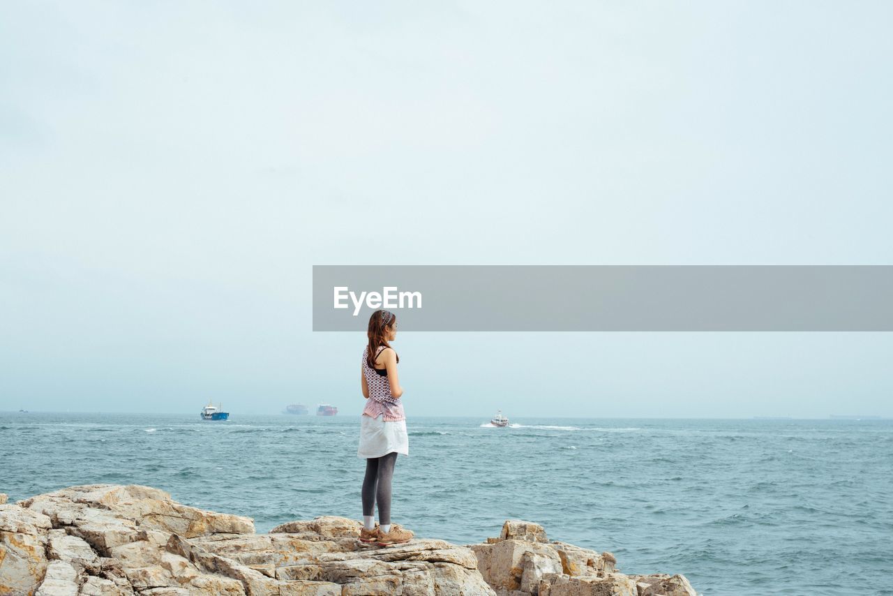 Rear view of woman overlooking calm sea