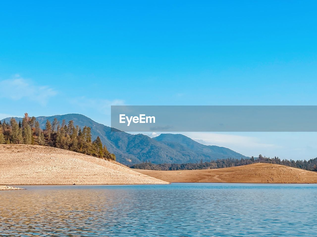 Scenic view of lake and mountains against blue sky