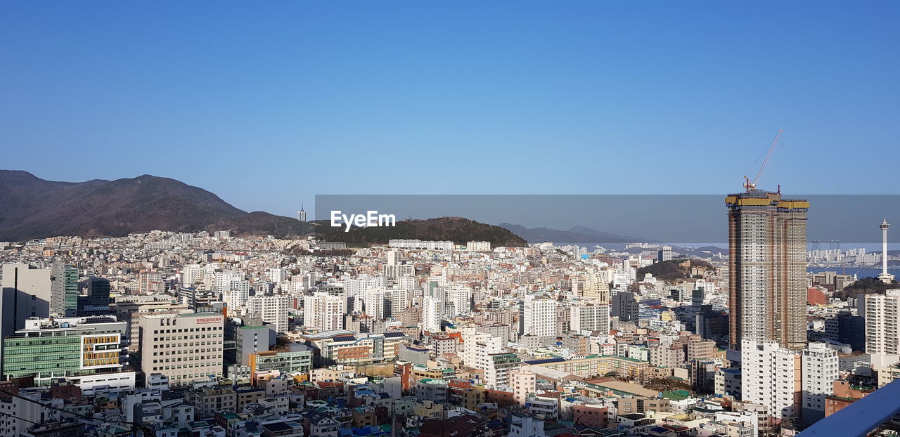 Aerial view of cityscape against clear blue sky
