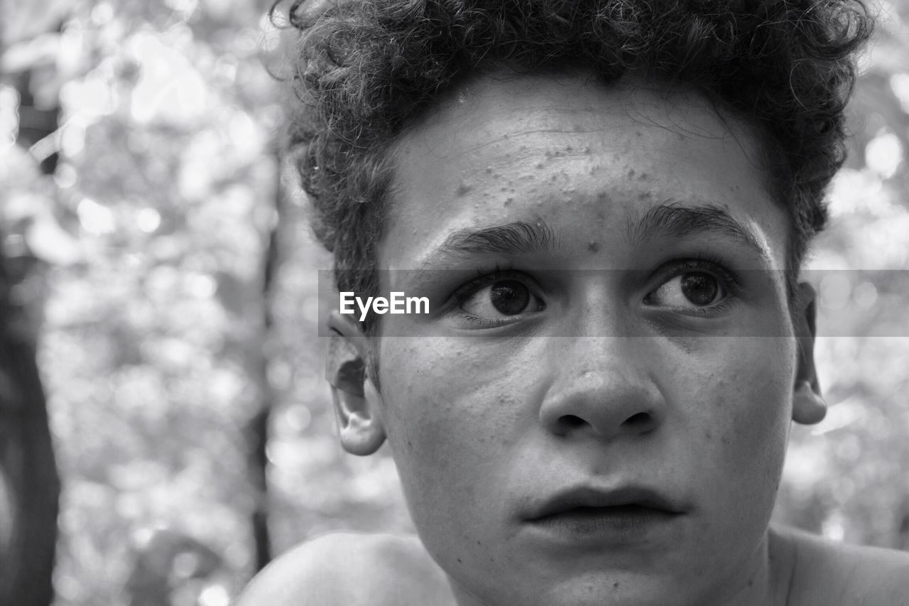 Close-up of young man looking away in forest