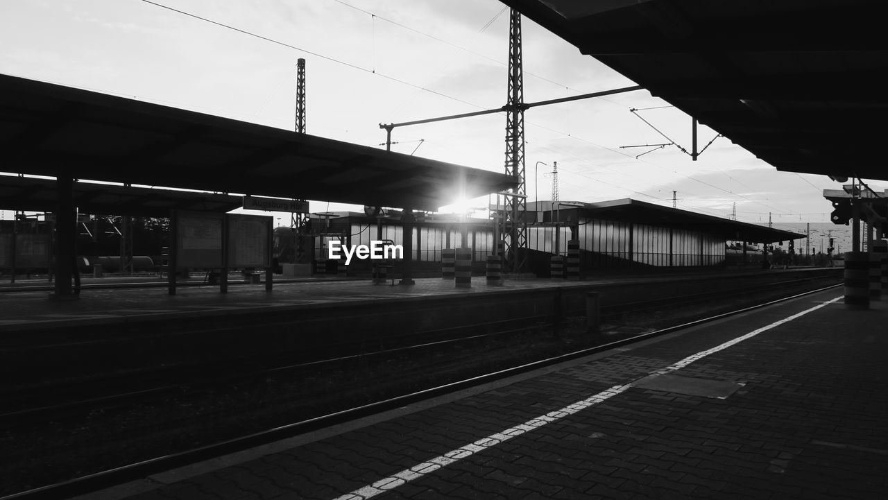 Empty railroad station against sky during sunset