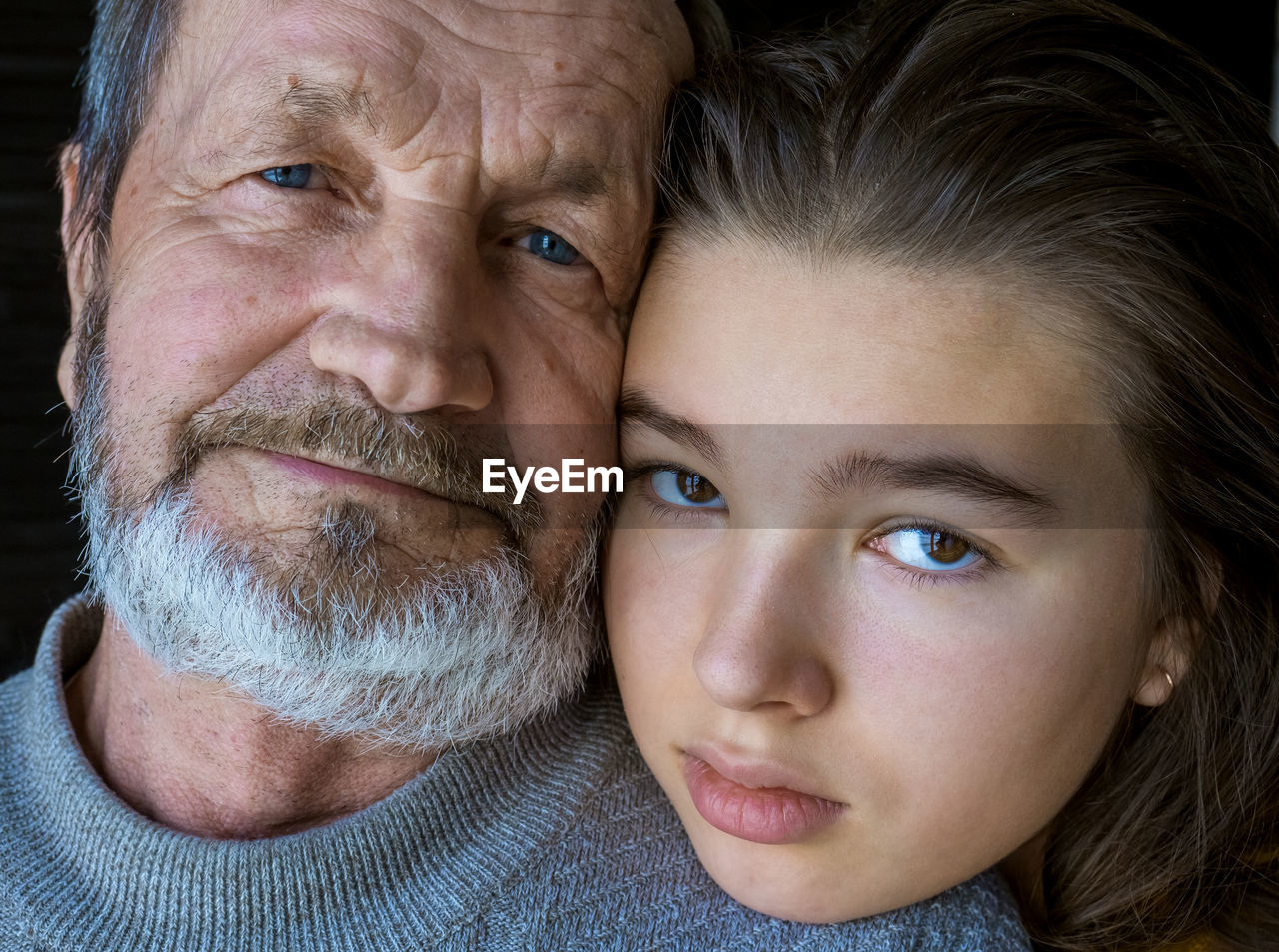 Close-up portrait of senior man with thoughtful granddaughter