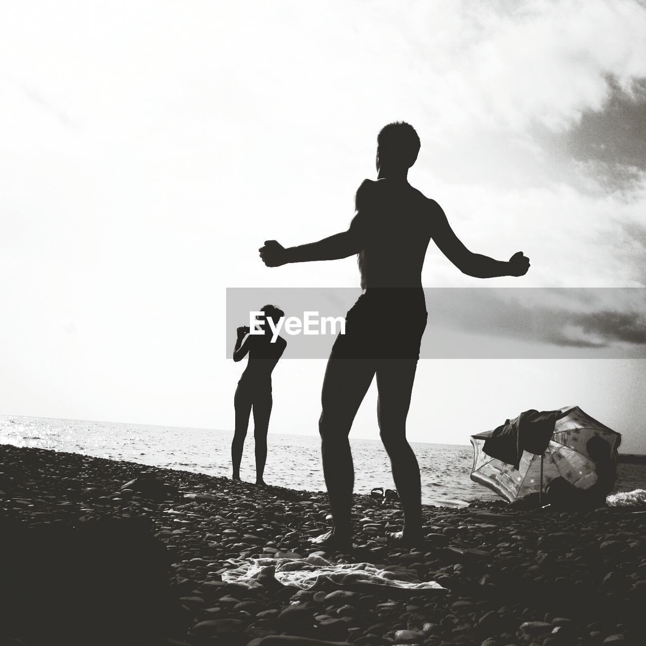 Full length rear view of silhouette man and woman standing at beach